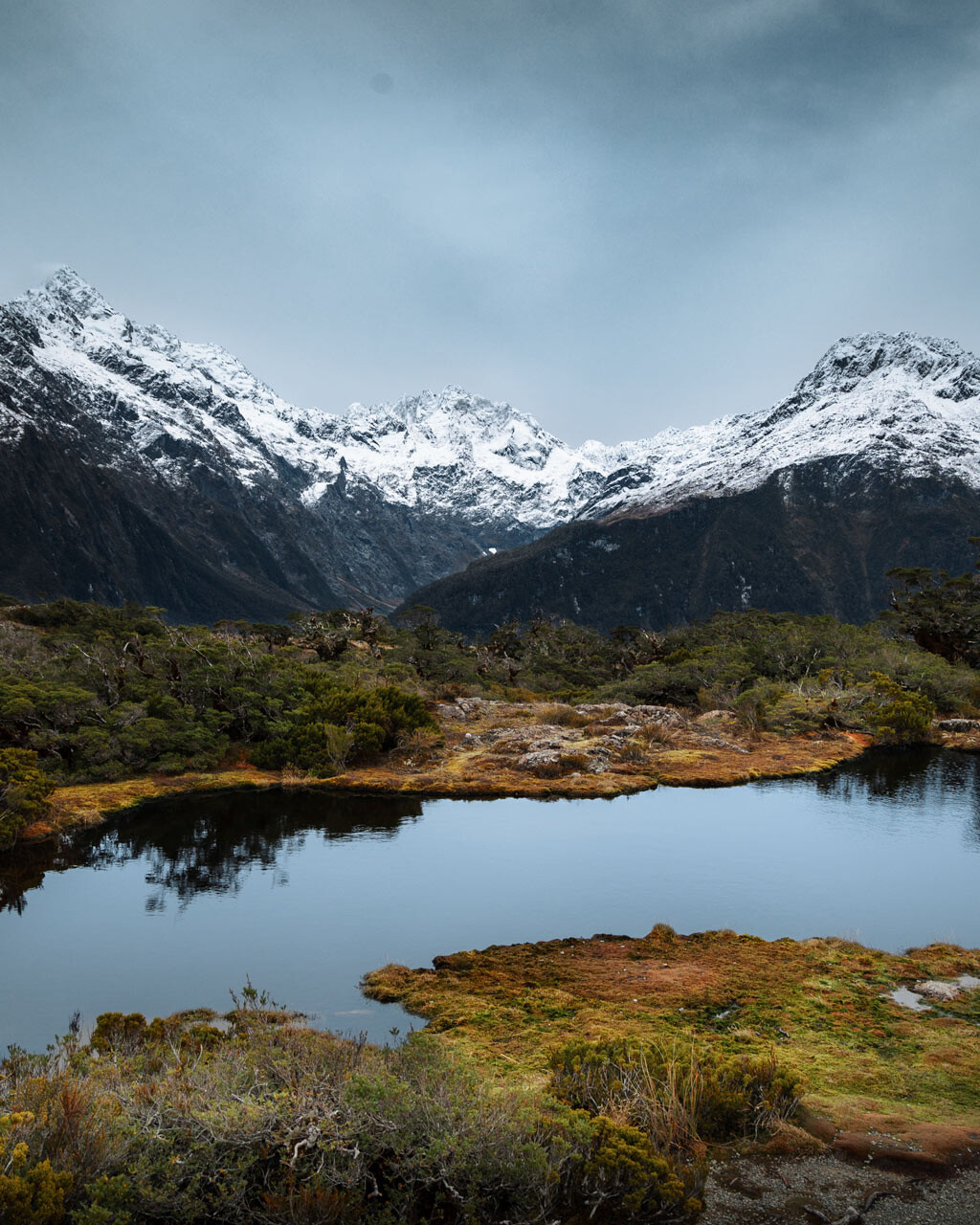 Beautiful Tarn bordered by snow capped peaks of Lake Marian from Key Summit